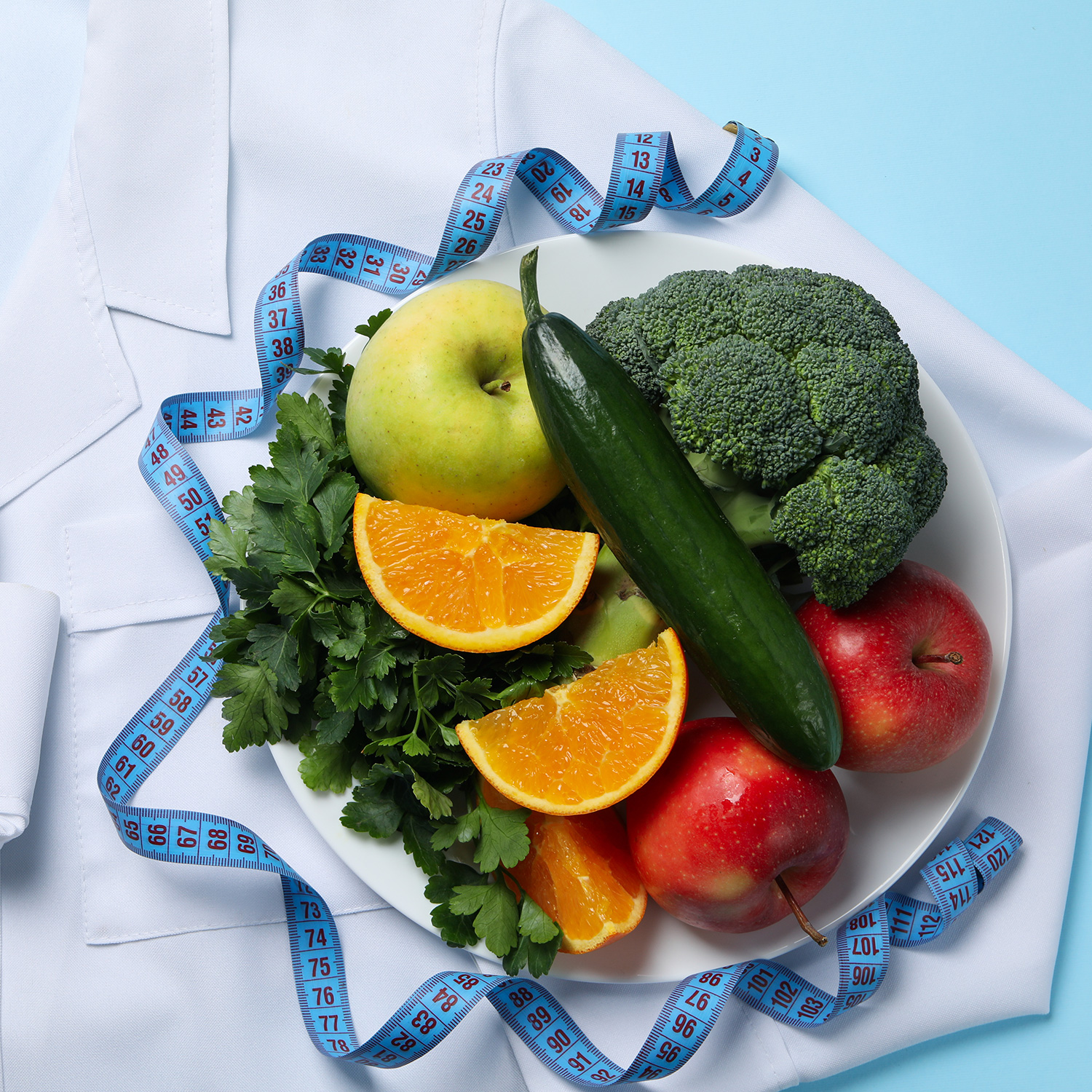 Doctors coat, healthy food and measuring tape on blue background